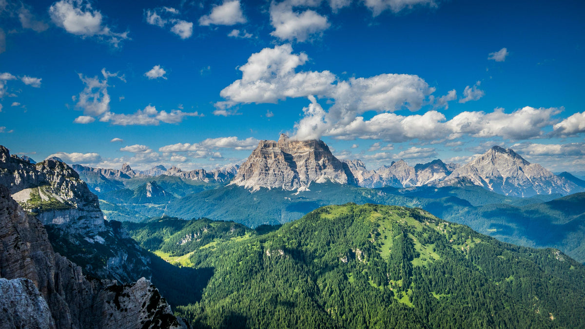 Panorama montano estivo con cielo azzurro e boschi, immagine categoria abbigliamento outdoor Monface Primavera-Estate.